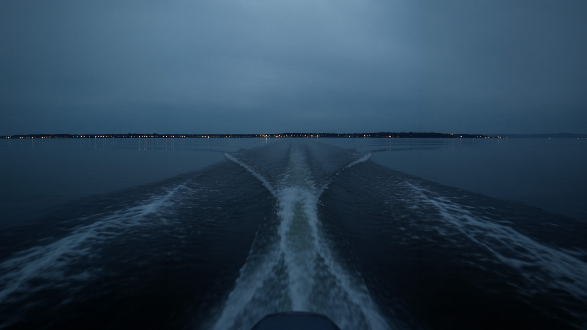 A speedboat wake across the lagoon at dusk