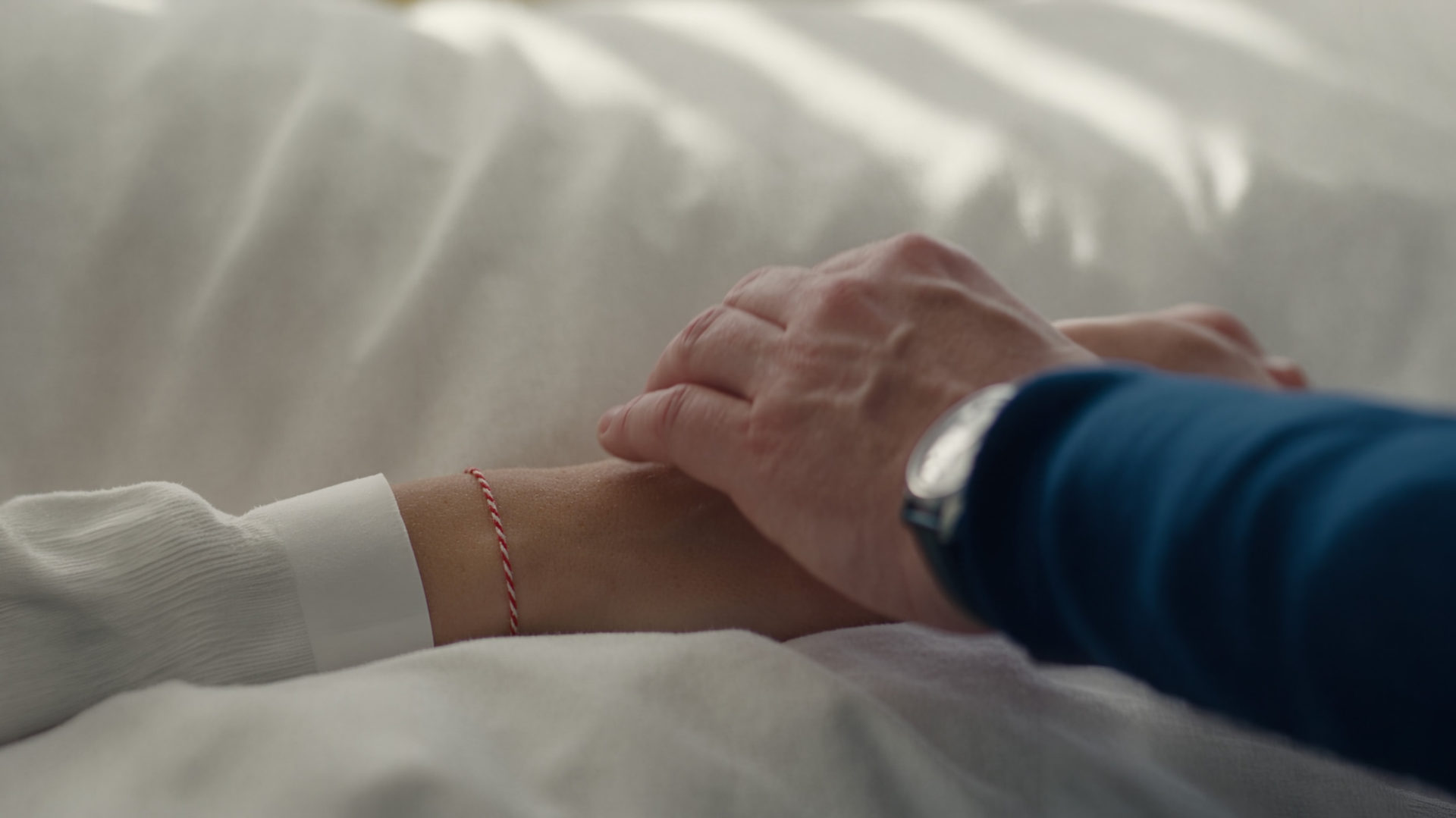 Two hands held on a hospital bed