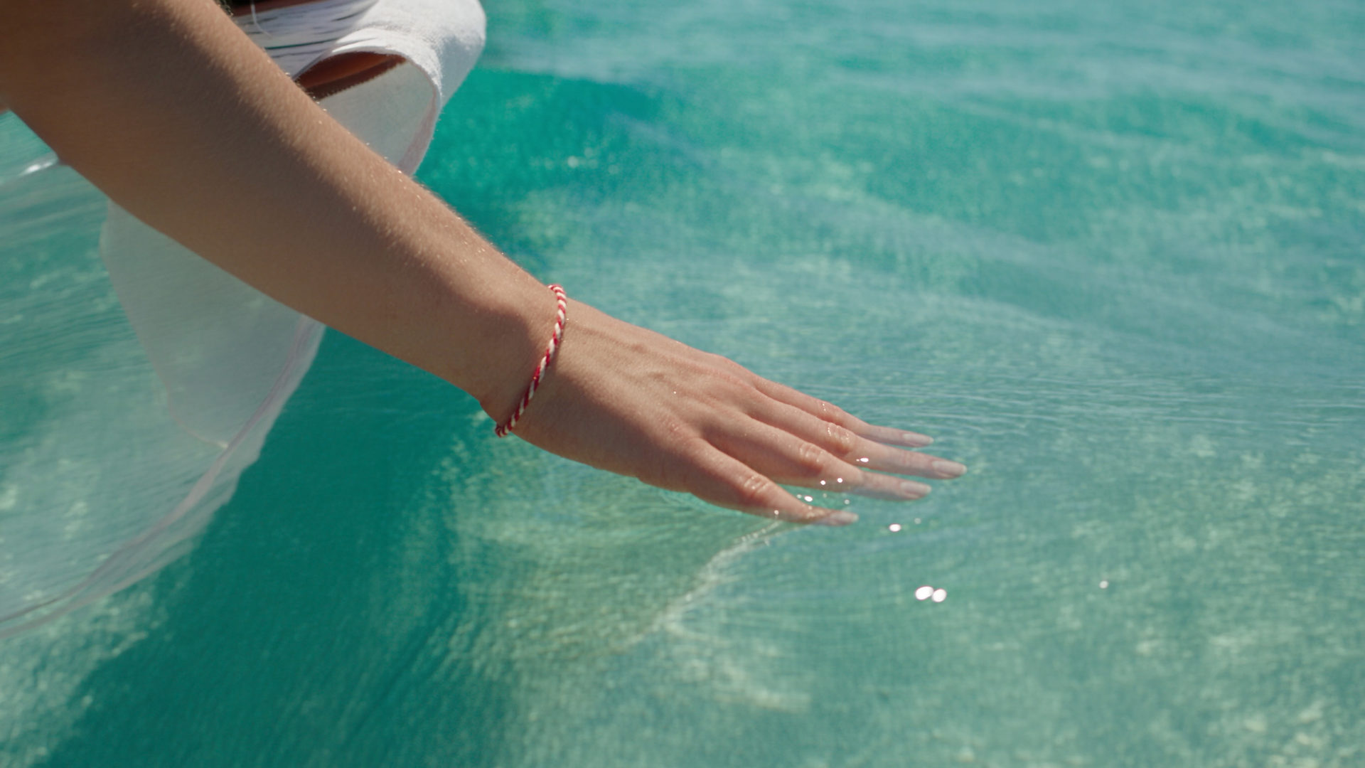 A hand trailing through a Maldivian lagoon